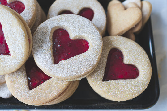 Macro image of Linzer cookies with heart cut out shape. Red raspberry jam filling. Valentines day, love and romance food concept image.