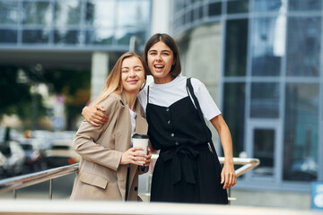 Good friends. Women in formal wear is outdoors in the city together