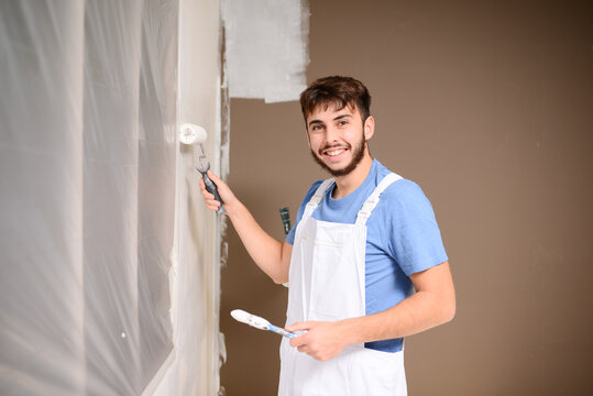 handsome young man professional painter in construction site wall painting renovation in a client house
