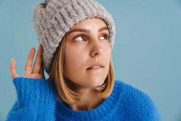 Young blonde woman wearing knit hat looking aside