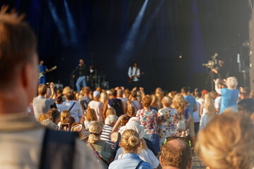 Fototapeta na wymiar People enjoying musical concert on large stage.