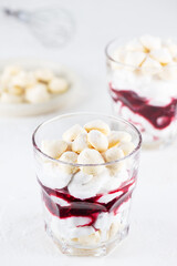 Homemade vegan dessert with meringue, coconut cream and cherries in glasses. Sugar, gluten and...