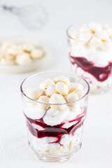 Homemade vegan dessert with meringue, coconut cream and cherries in glasses. Sugar, gluten and lactose free.