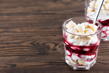 Homemade vegan dessert with meringues, coconut cream and cherries in glasses on a wooden table. Sugar, gluten and lactose free. Horizontal orientation, copy space.