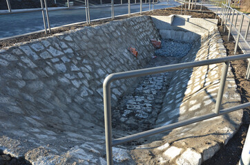 Sewer gutter paved with granite stone and dikes drains rainwater by ditch at the highway into the...