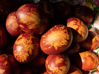 Macro shot of Easter eggs decorated with natural plants and flower blossoms boiled in onions peels. Traditional way to create yellow patterns of plants on brown eggs in bright sunlight