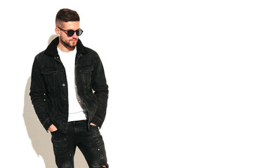 Portrait of handsome confident model. Sexy stylish man dressed in biker leather jacket and black jeans. Fashion hipster male isolated on white in studio. In sunglasses