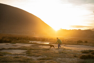 Obraz premium a woman playng with her dog at sunset
