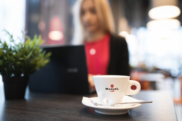 woman working on her laptop in cafe drinking coffee blonde red sweater plant on table