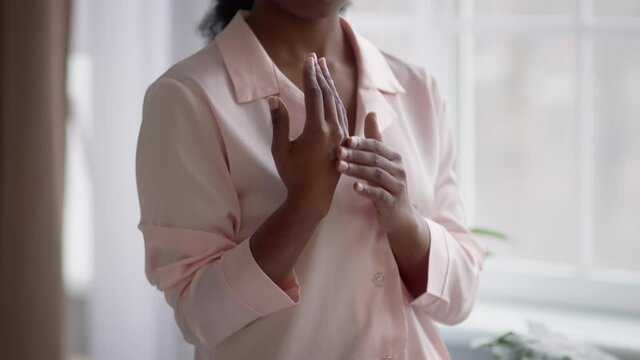 Unrecognizable Black Female Applying Cream Moisturizer On Hand At Home