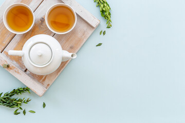 Two cups of tea with white teapot, top view