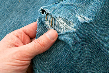 Man explore hole in ripped jeans before sew up it