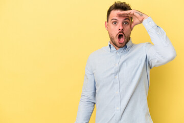 Young caucasian man isolated on yellow background looking far away keeping hand on forehead.