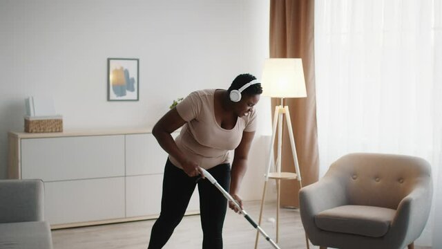 Black Lady Cleaning House Mopping Floor Wearing Headphones Indoor