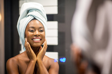 Close up smiling young black woman hands touching face while looking in mirror