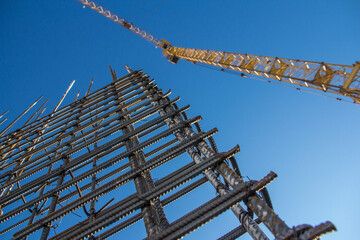 A reinforced steel rebar foundation work and tower crane against the blue sky. Construction....