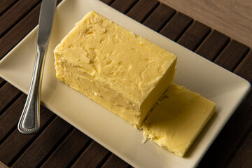Bio butter on a white plate with a knife on a brown wooden mat