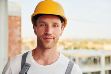 Building of modern city. Young man working in uniform at construction at daytime