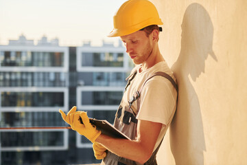 Illuminated by sunlight. Young man working in uniform at construction at daytime