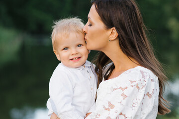 A mother kisses her two-year-old son. The son is happy and smiling. Mother's day