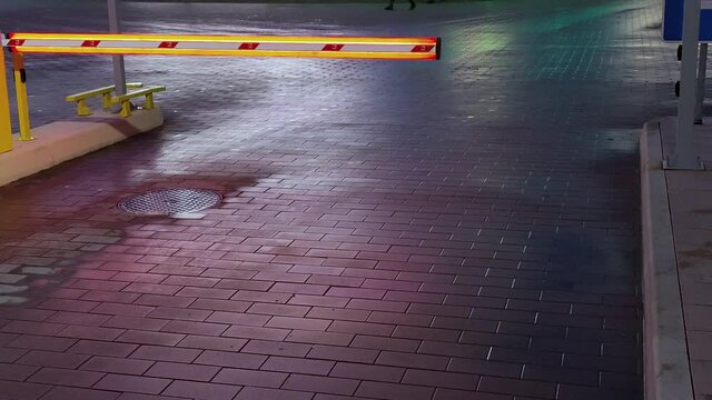 View of a luminous automatic barrier for entering a paid parking lot at night in the city