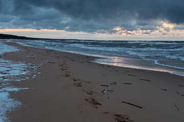 dark clouds over sea on a cold winter sunset evening snow on beach
