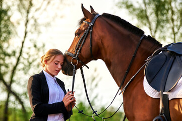 Fototapeta premium Beautiful horse rider girl stands near a horse on a farm 