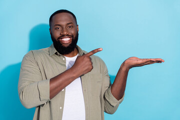 Photo of young african man indicate finger product advertise select discount isolated over blue...