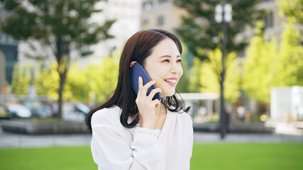 屋外でスマホを使って通話する女性