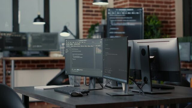Computer monitors displaying parsing code in empty it agency office and computers compiling data algorithms in background. Artificial intelligence servers cloud computing in data room.