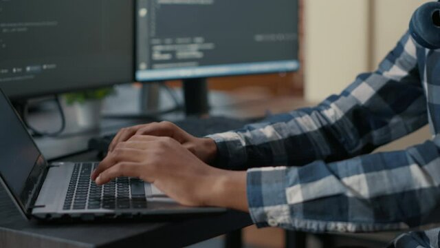 Closeup of programer hands typing machine learning code on laptop keyboard in front of computer screens with programming interface. System engineer writing algorithm for online cloud computing.