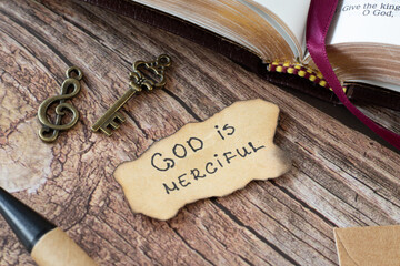 God is Merciful, handwritten Bible quote with an old, vintage key and treble clef on a wooden...