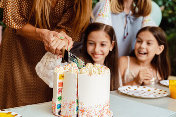 White girl cutting cake with her mother during birthday party