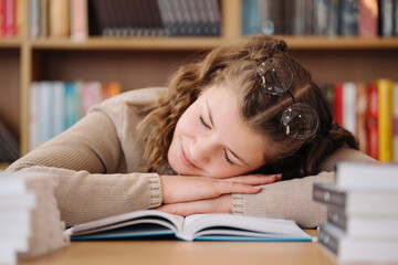 Young women got asleep on the books while studying, reading glasses on head