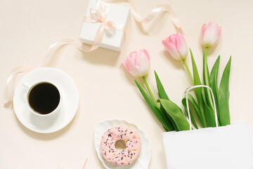 Tulips, gift box and coffee on a beige background. Flat lay. 8 March, International Women's Day. Valentine's Day.