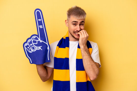 Young Sports Fan Caucasian Man Isolated On Yellow Background Biting Fingernails, Nervous And Very Anxious.