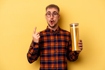 Young caucasian man holding spaghettis jar isolated on yellow background having some great idea, concept of creativity.