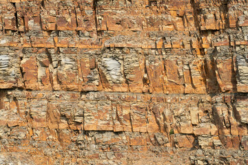 A fragment of a sheer cliff of folded layered fractured rock. Texture. Copy space.