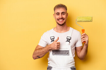 Young painter man isolated on yellow background smiling and raising thumb up