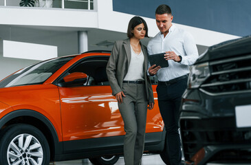 Modern vehicles. Man in formal wear helping customer with choice of the automobile
