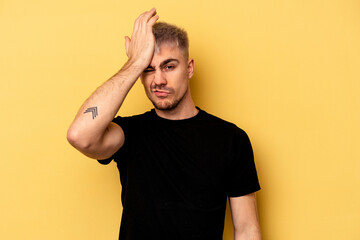 Young caucasian man isolated on yellow background forgetting something, slapping forehead with palm...