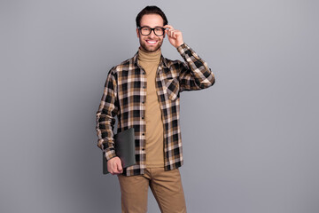 Photo of smart clever man wear plaid shirt arm spectacles holding modern gadget isolated grey color background