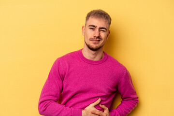 Young caucasian man isolated on yellow background having a liver pain, stomach ache.