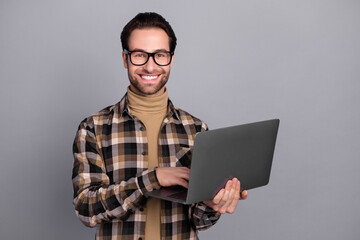 Photo of charming cheerful man wear plaid shirt spectacles working modern gadget isolated grey color background