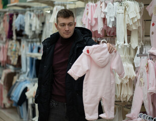 Photo of a man choosing comfortable clothes for his future baby.
