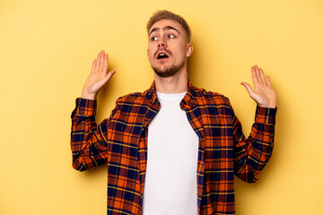 Young caucasian man isolated on yellow background being shocked due to an imminent danger