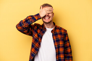 Young caucasian man isolated on yellow background covers eyes with hands, smiles broadly waiting for a surprise.