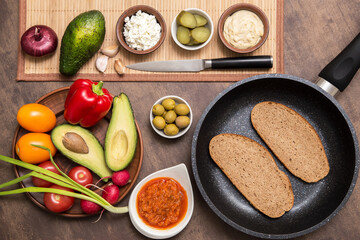 Ingredients for cooking vegan vegetarian sandwich with different vegetables and toast of rye fried bread on kitchen. Healthy diet food concept