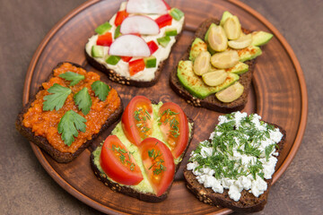 Set different vegan, vegetarian sandwiches. Homemade smorrebrod with vegetables, avocado, tomato, olive, hummus, cucumber, cottage cheese