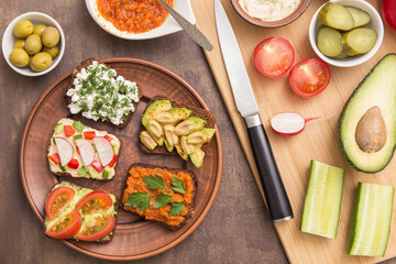 Fototapeta na wymiar Healthy fast food. Vegan, vegetarian sandwiches with hummus, tomato, avocado, cottage cheese, vegetables and greens. Top view, flat lay